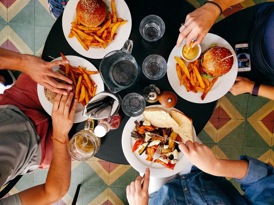 Mehrere Personen teilen sich Pommes und Snacks an einem Tisch